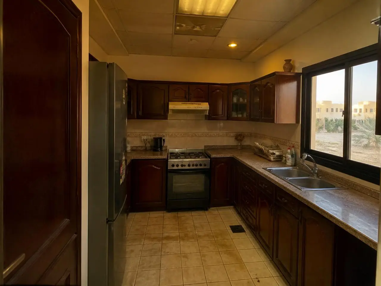 Dark outdated kitchen with brown wood cabinets before renovation in JVC Dubai